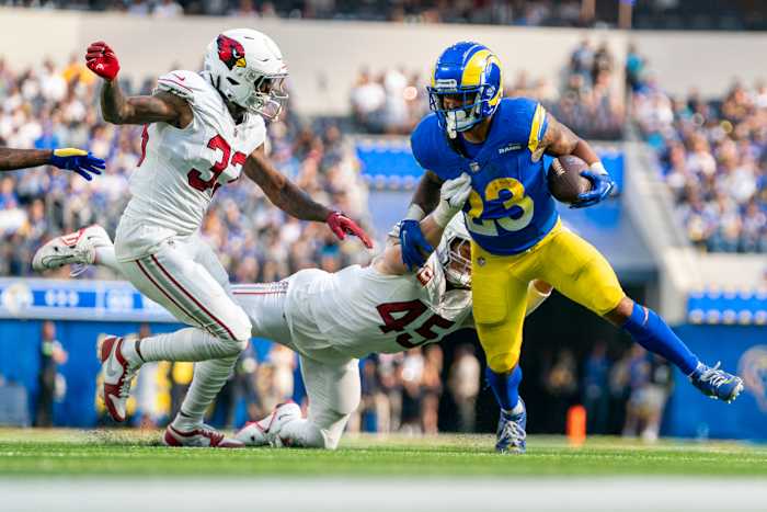 Los Angeles Rams running back Kyren Williams (23) runs the football against Arizona Cardinals cornerback Antonio Hamilton Sr. (33) and linebacker Dennis Gardeck (45) during the third quarter at SoFi Stadium